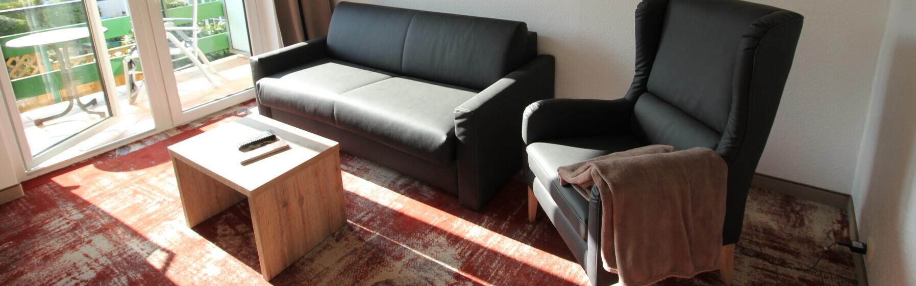 Unsere Junior Suite mit Balkon. Hier sind gemütliche Sofa und Sessel mit kleiner Tisch, hinten ist auch Eingang zur Balkon.