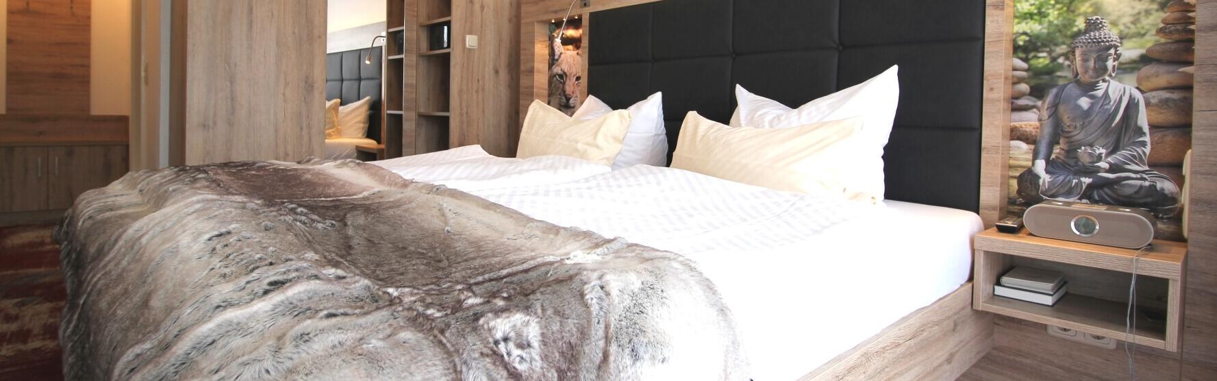 Unsere Junior Suite mit Balkon. Hier sind gemütliche Bett mit große Kissen und schöne Bild.