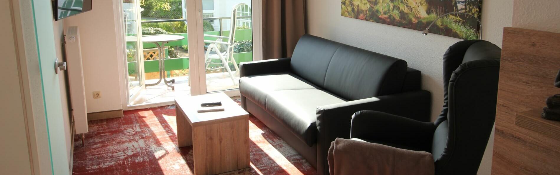 Unsere Junior Suite mit Balkon. Hier sind gemütliche Sofa mit Sessel, neue Fernsehen kleiner Tisch.